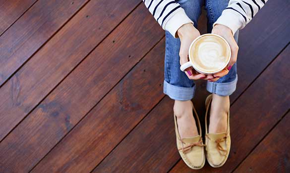a woman sitting on a gorgeous hardwood floor and holding a cup of coffee